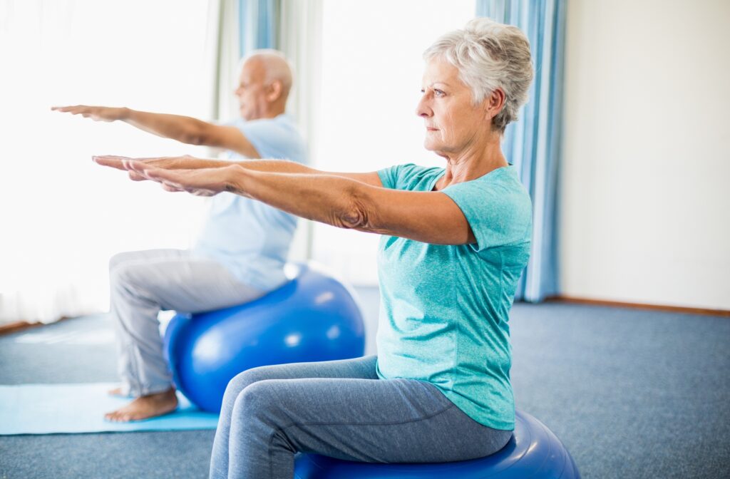 A senior couple sitting on exercise balls strengthening their balance as they both stretch their arms out in front of them