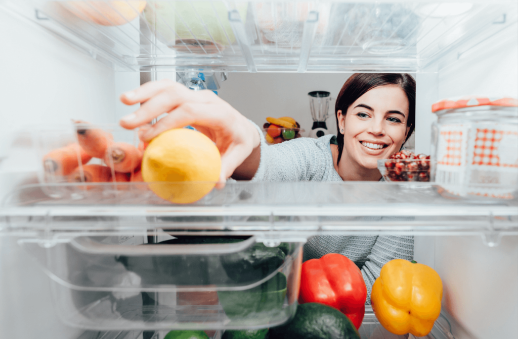 Young woman putting a lemon inside her refrigerator