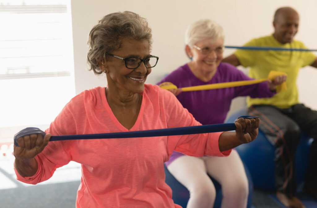 a group of seniors in memory care use exercise bands to stretch their arms