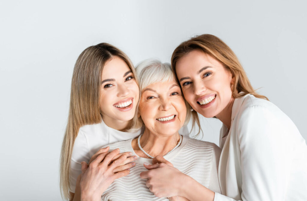 Three generations of women smiling while hugging each other.