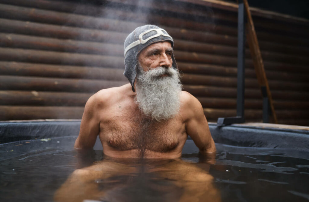 A stern-looking senior man in a outdoor hot tub.
