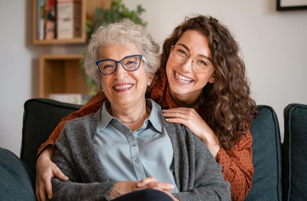 An adult child embraces their mature parent while in assisted living