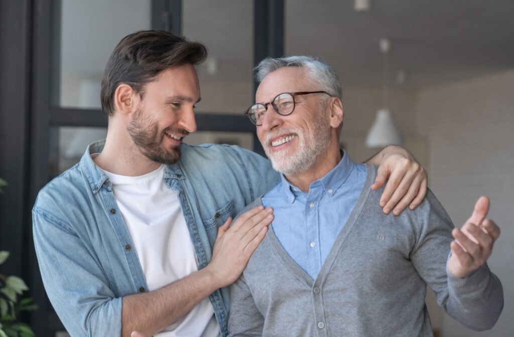 An older adult and their adult child laughing and smiling together.